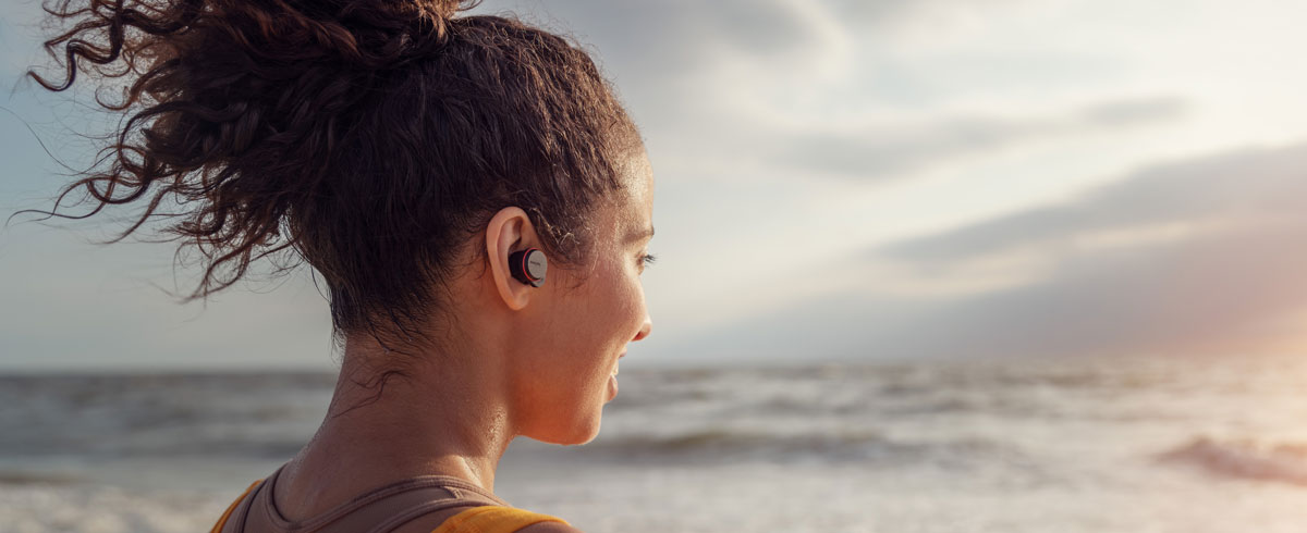 Woman using true wireless headphones on the seaside